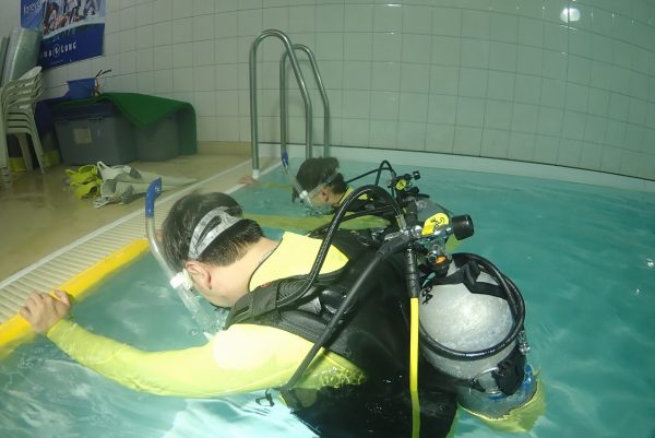 ダイビングプールで呼吸の練習をする男性の写真