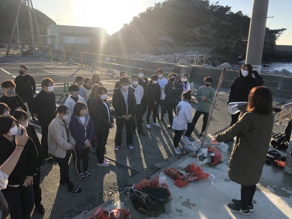 複数人に向けて拾ったゴミの紹介をしている写真